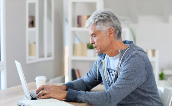 Senior man reading planning articles on laptop computer